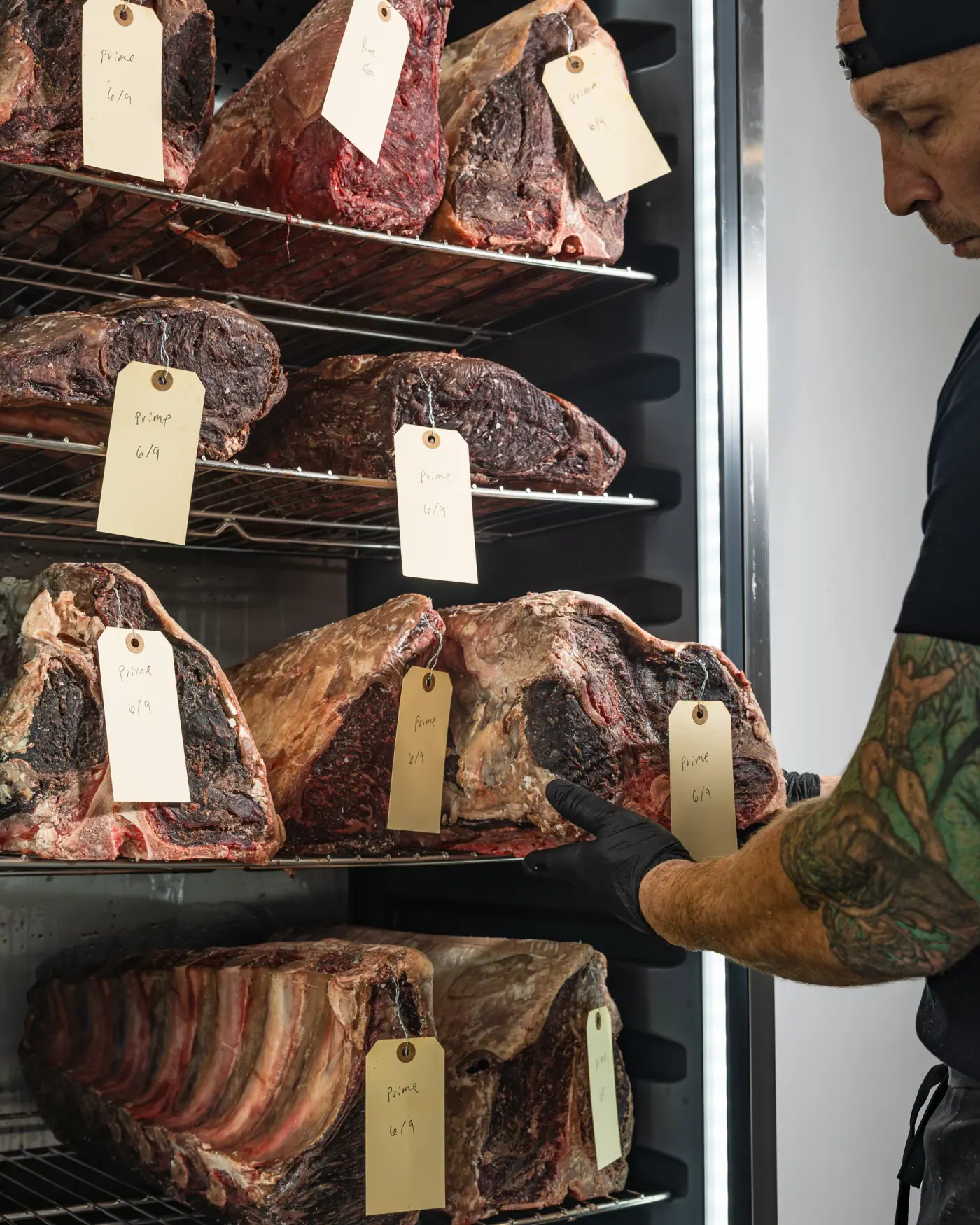 A butcher inspecting primals inside the dry-age cellar