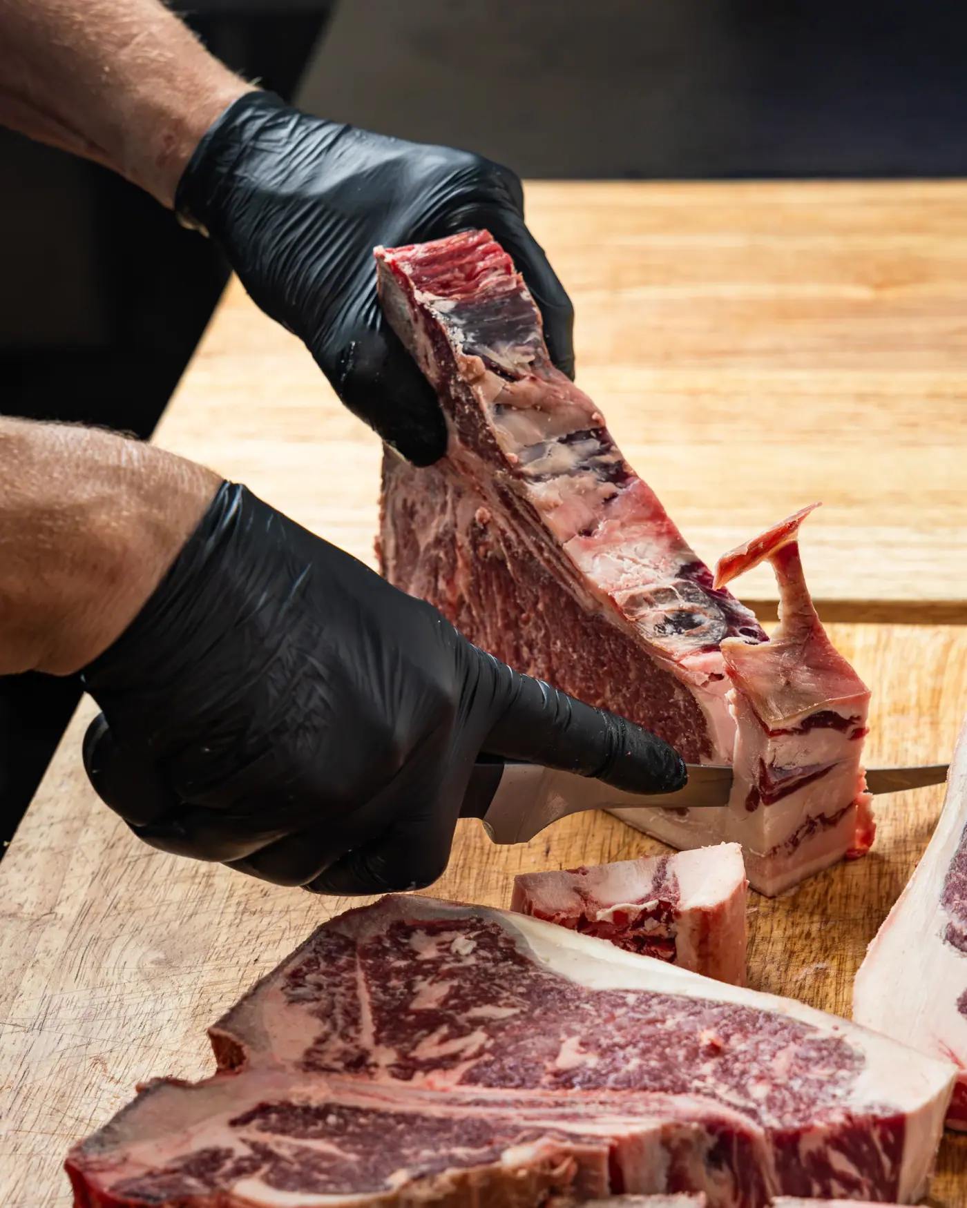 Hands trimming a porterhouse at the block