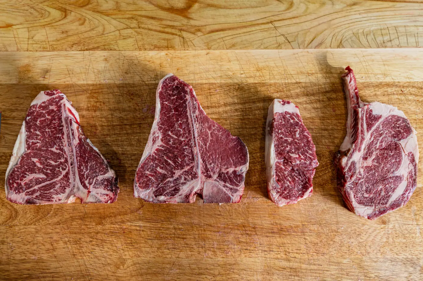 Porterhouse, T-bone and tomahawk lined up on the board