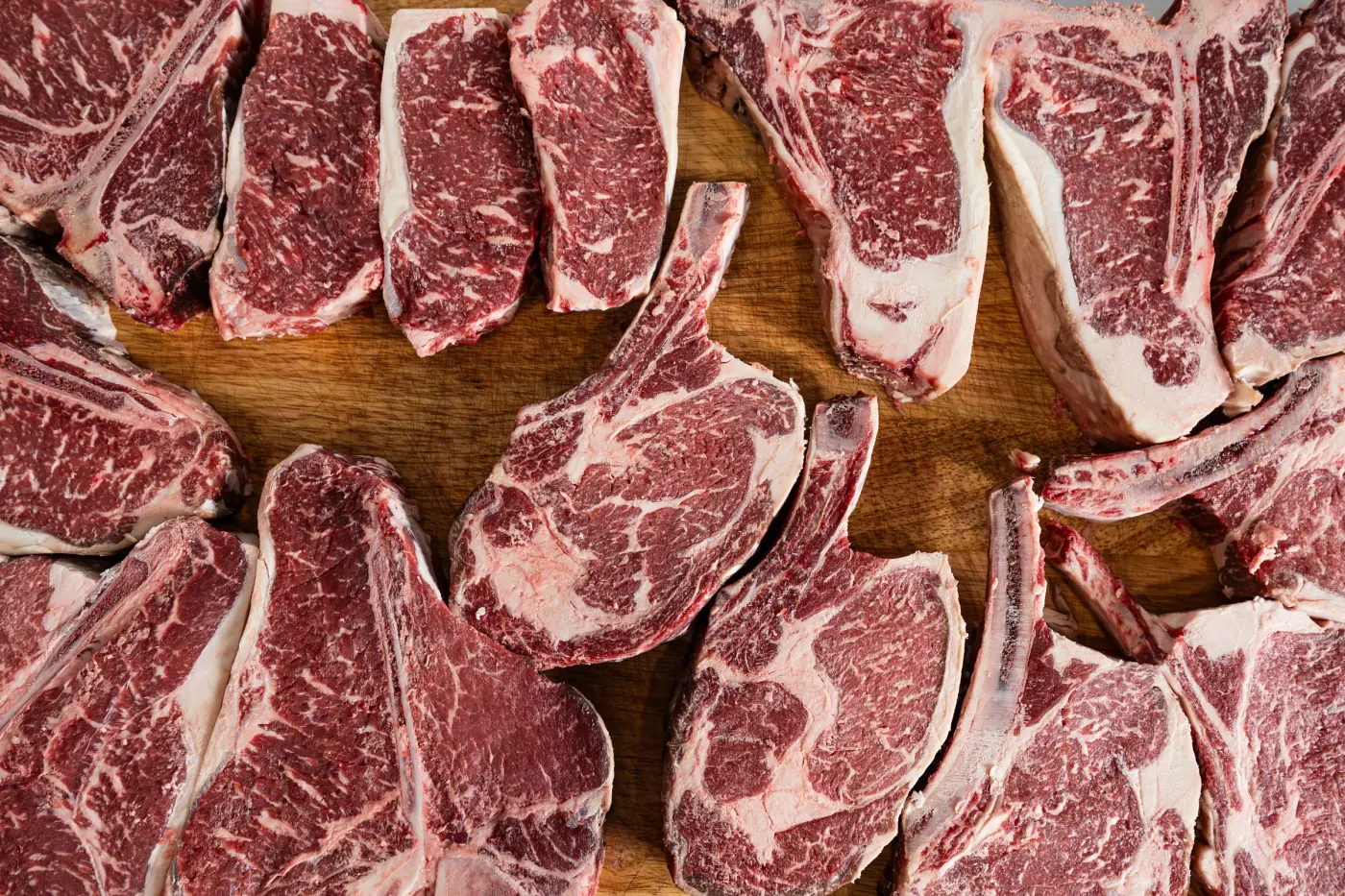 An overhead spread of ribeye and tomahawk steaks on the block